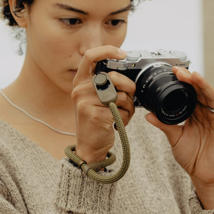 Person holding a camera with a Kelp Rope Cuff on their wrist