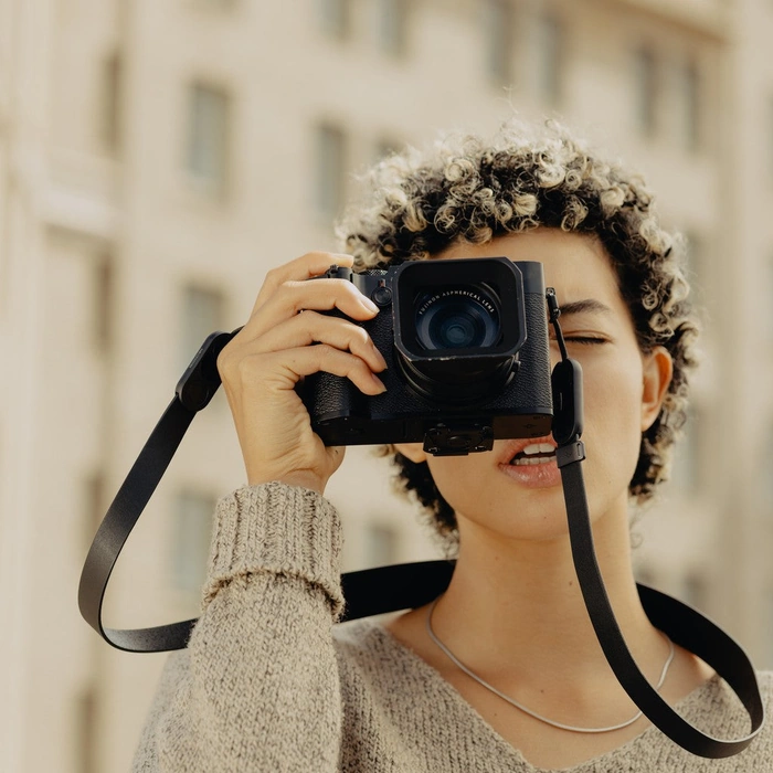 Person holding a camera with Black Form Leather Strap Standard in a blurred building background