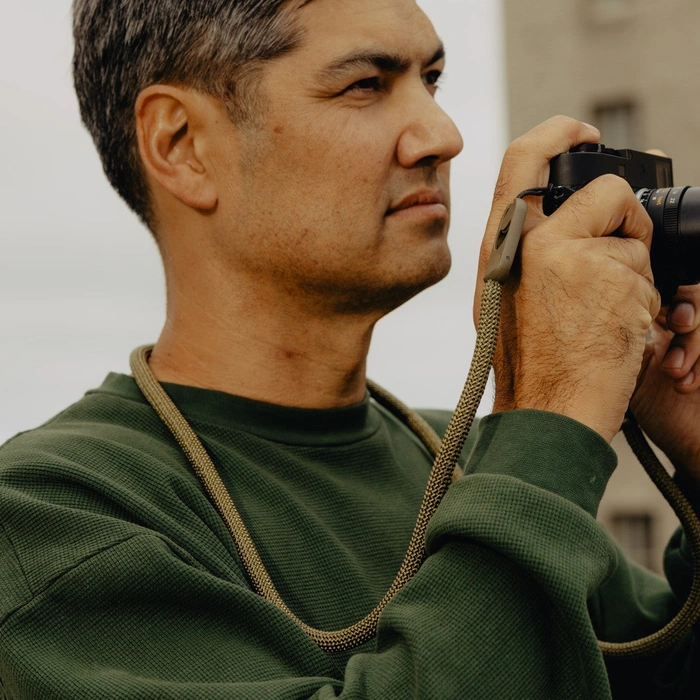Man taking photo with a camera attached to long kelp rope strap