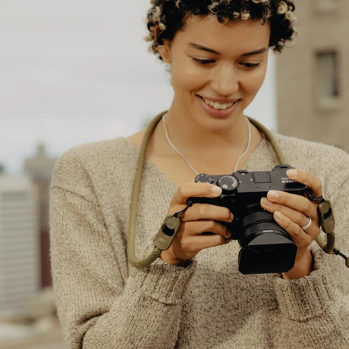 Woman holding a camera and smiling outdoors