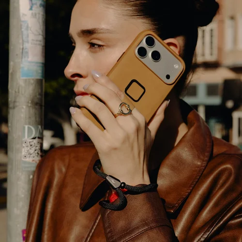 Person wearing a brown leather jacket holding a phone with a Mobile Cuff Black